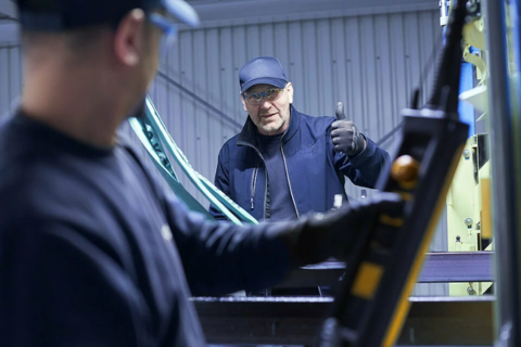 Employee on a scissor lift installing media supply on the ceiling of a factory.